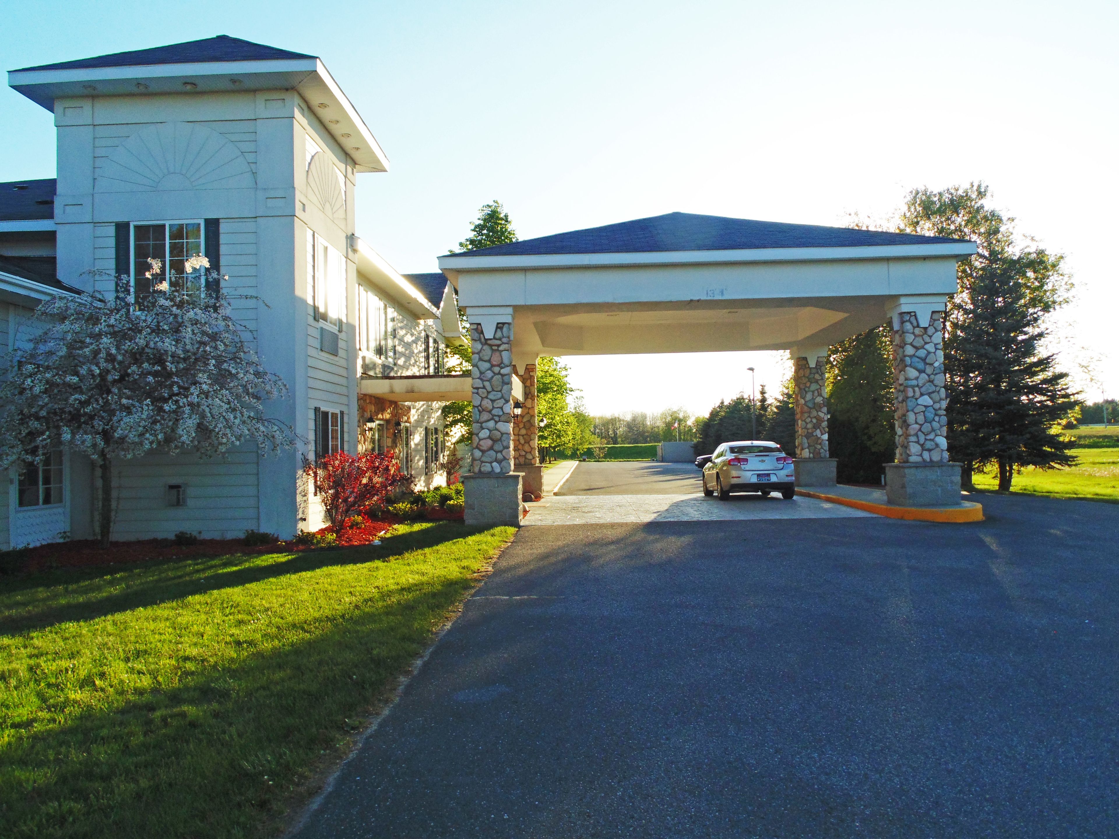 A two-story house with a covered driveway and a stone pillar.