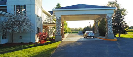A two-story house with a covered driveway and a stone pillar.