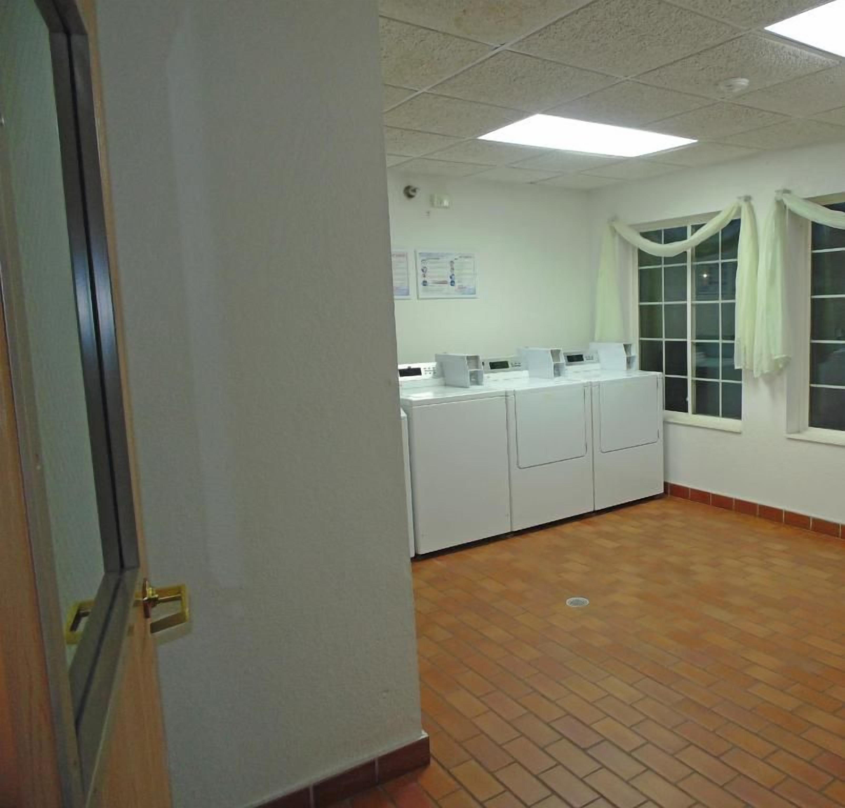 A room with a tiled floor, a window with curtains, and a white cabinet with a computer.