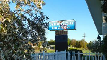 Un letrero para American Inn & Suites con una cerca blanca de piquetes al frente.