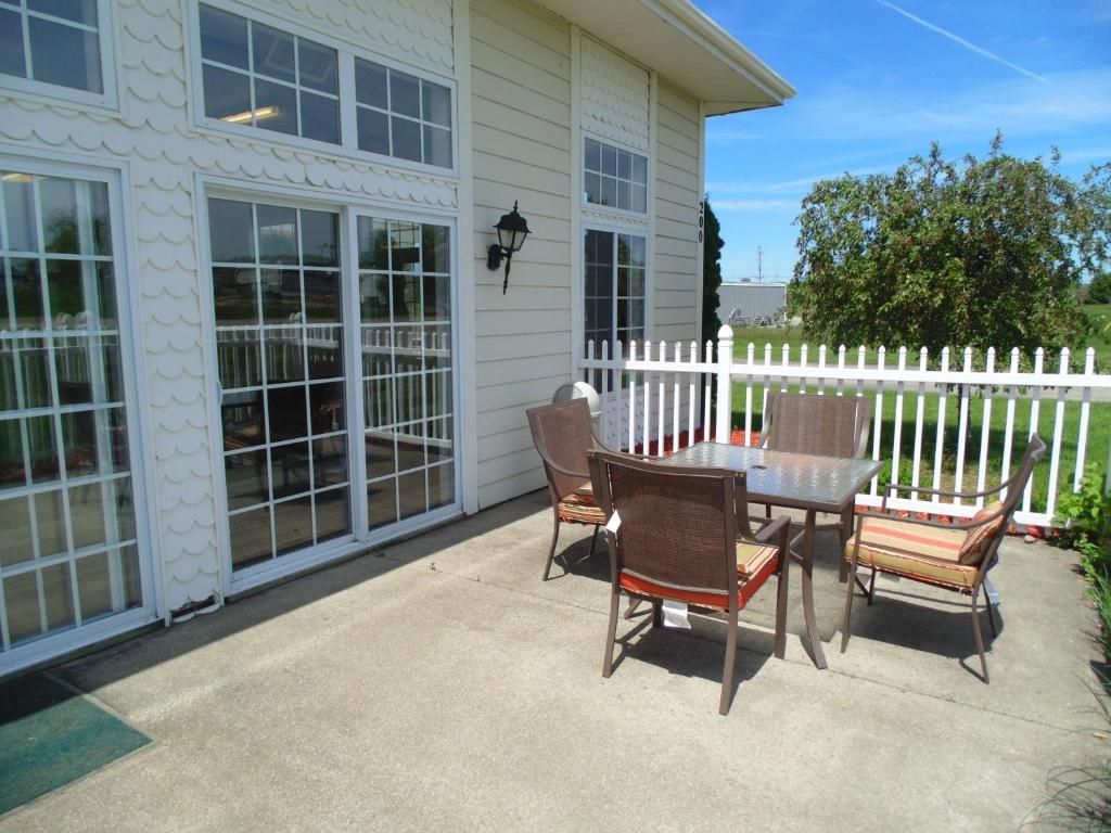 A patio with a table and chairs, a white fence, and a building with large windows.