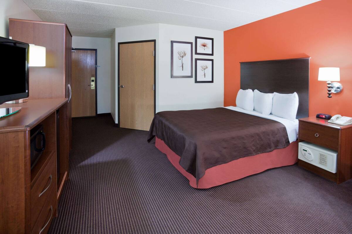Habitación de hotel con cama, escritorio con computadora, armario y puerta.