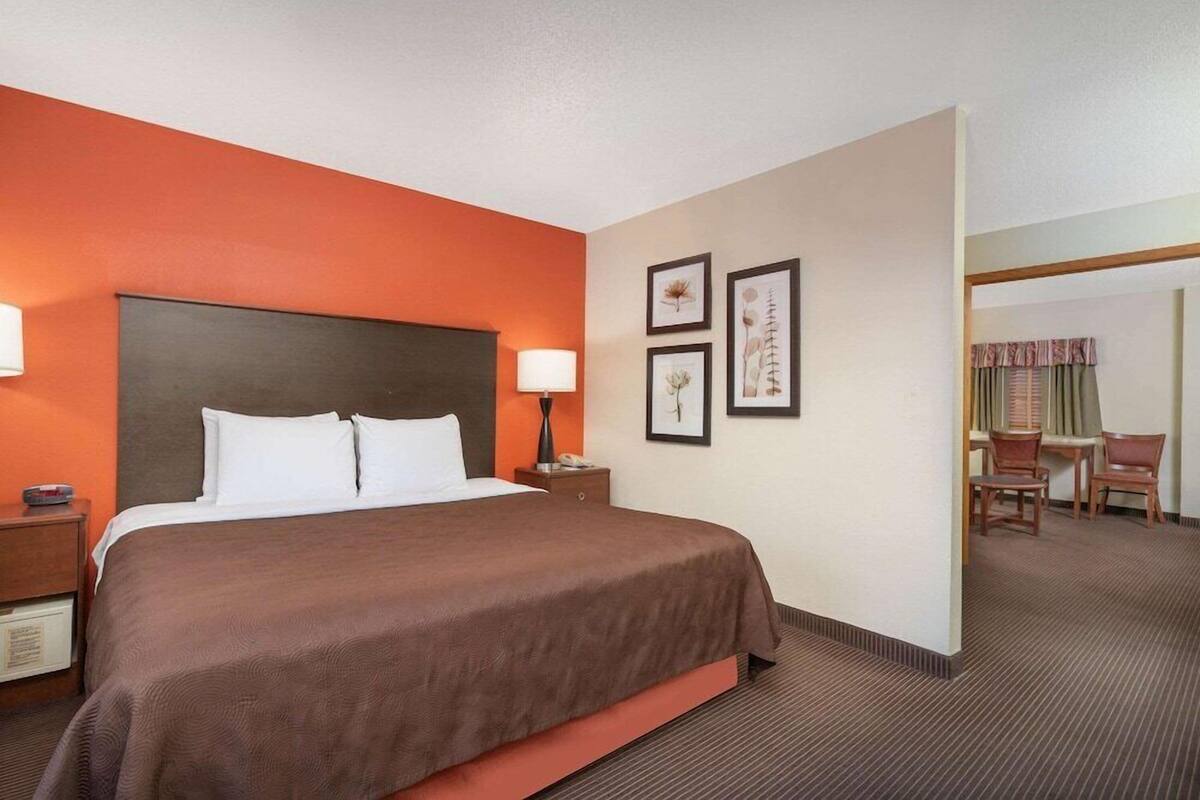 Una habitación de hotel con una cama grande, una mesita de noche, una lámpara y cuadros en la pared.