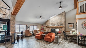A spacious lobby with a stone fireplace, wooden floors, and seating areas. - AmericInn by Wyndham Coon Rapids (Coon Rapids)