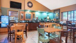 A restaurant with wooden tables and chairs, a coffee machine, and a chalkboard menu. - AmericInn by Wyndham Coon Rapids (Coon Rapids)