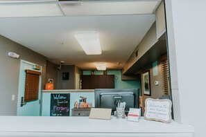 Un espace d’accueil avec un tableau noir, un ordinateur et un panneau indiquant le mot de passe du Wi-Fi.