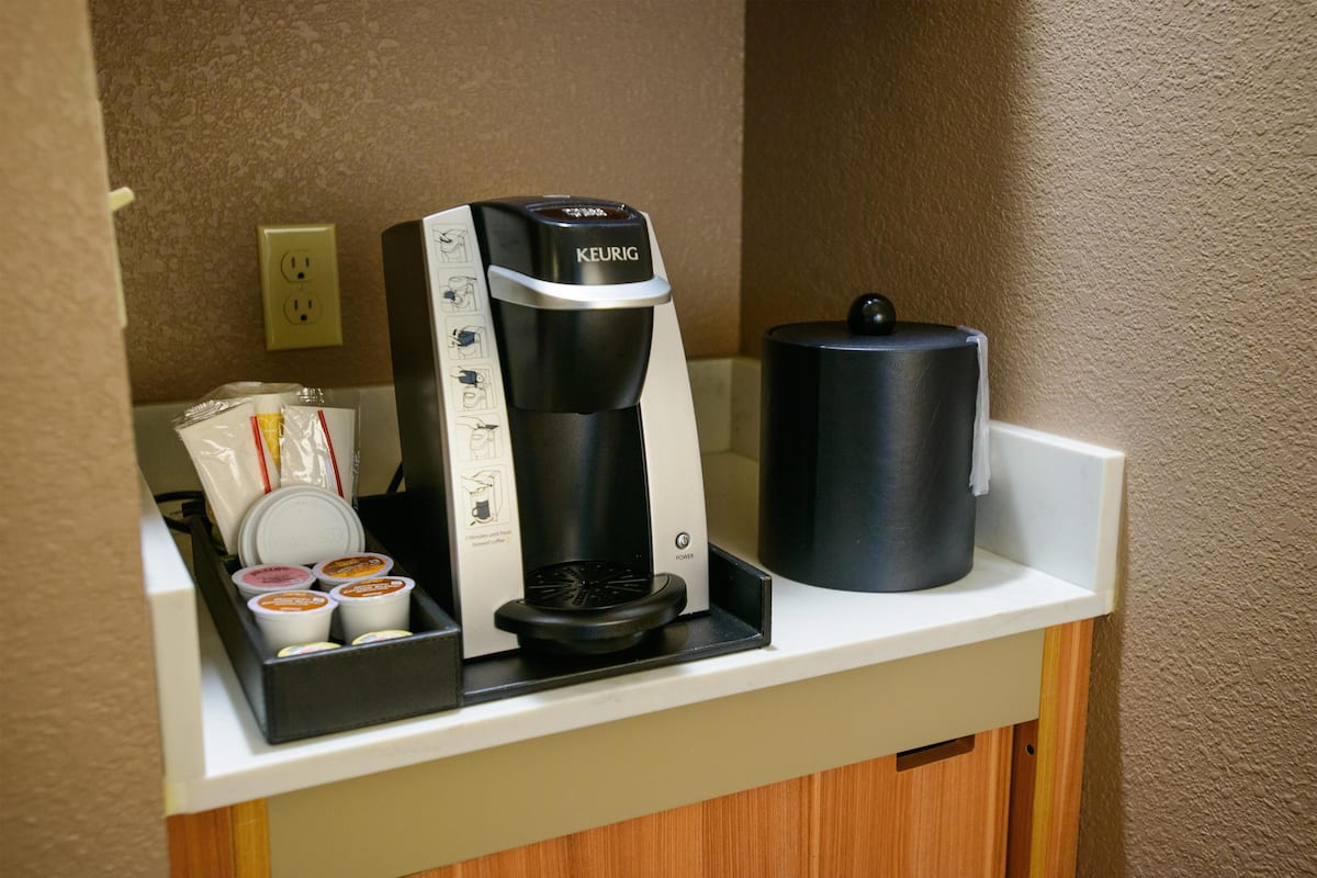 A coffee maker with a coffee pod holder and a water container on a countertop.