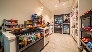 A grocery store with refrigerated and frozen sections, shelves stocked with snacks, and a variety of beverages.