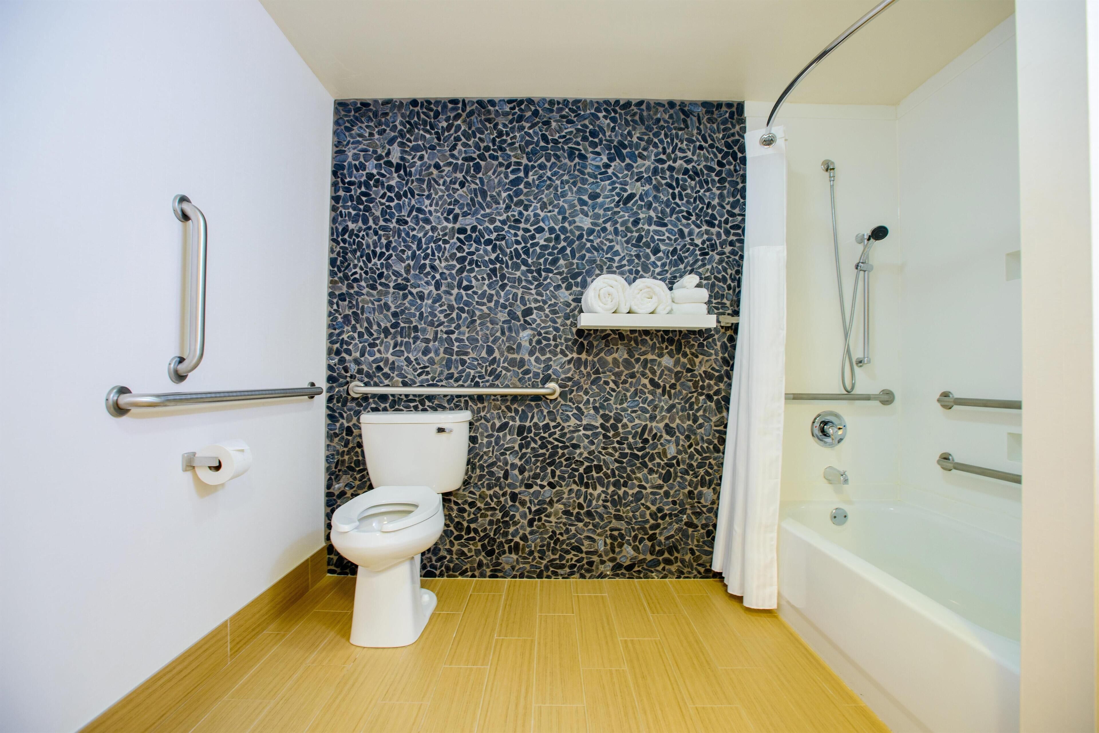 A bathroom with a toilet, a shower, and a mosaic wall.