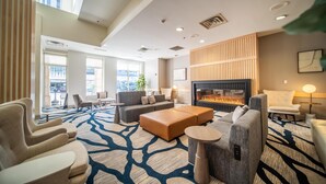 A spacious lobby with a large seating area, a fireplace, and large windows providing natural light.