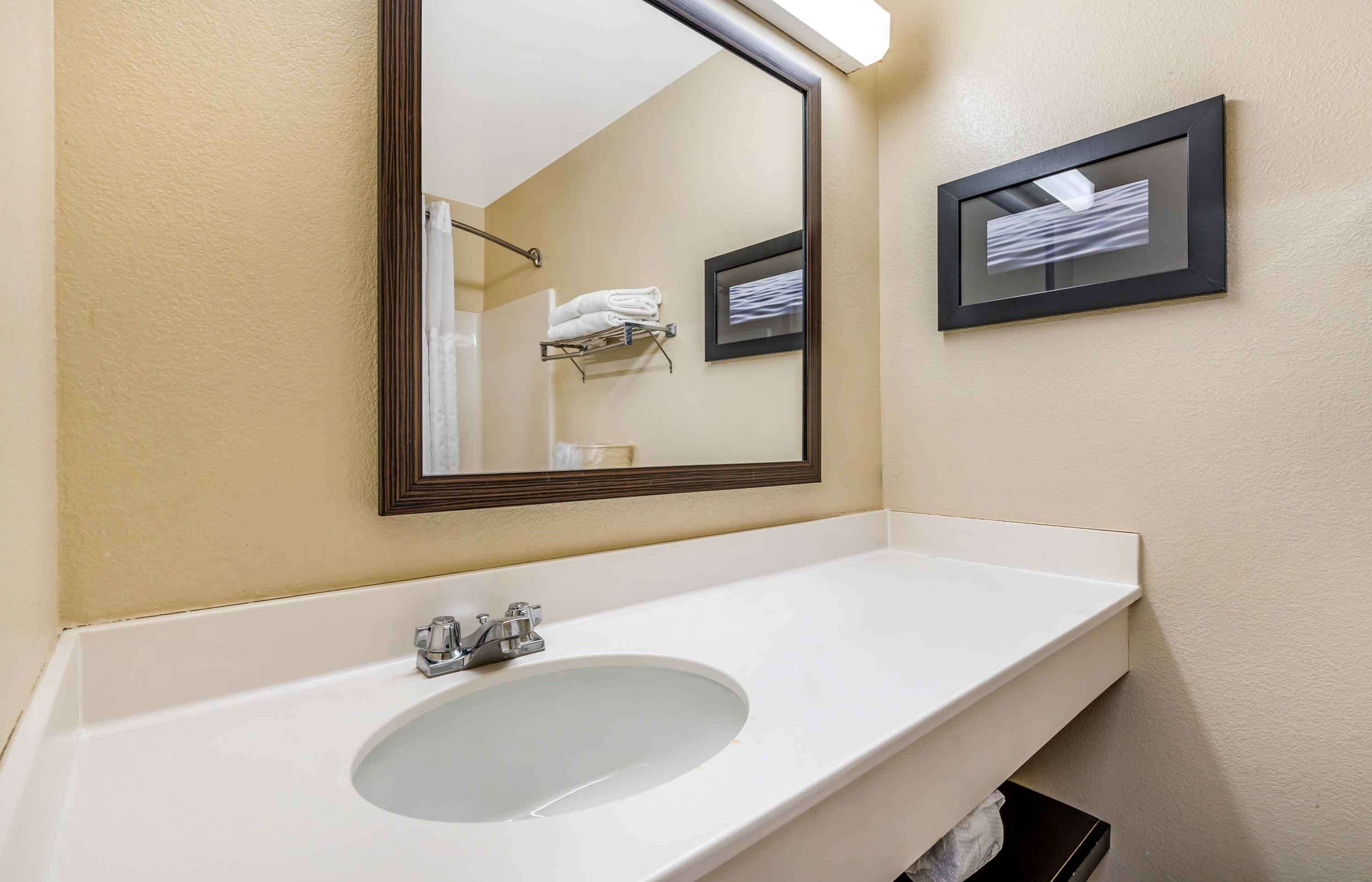 A bathroom with a white sink, a mirror, and a towel rack.