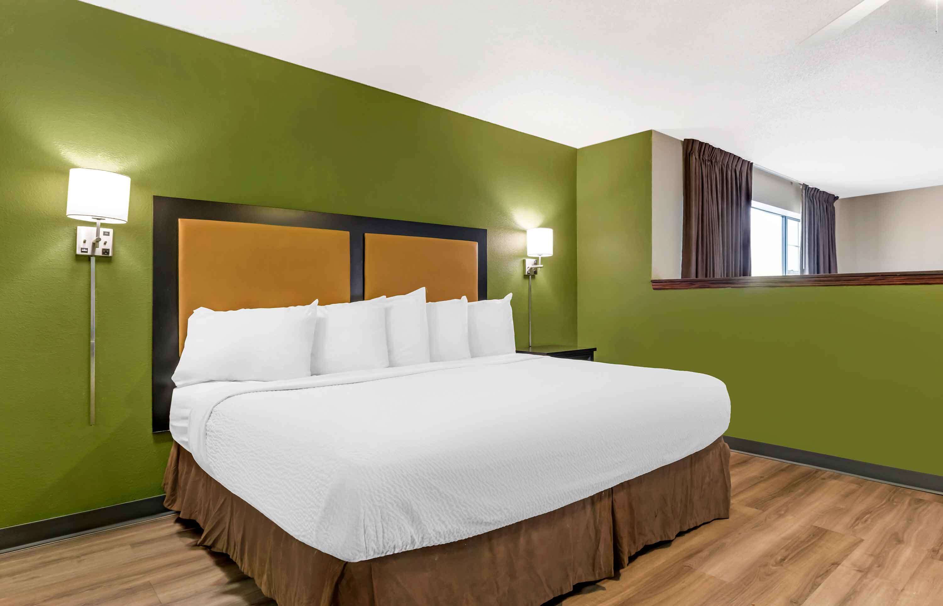 Une chambre d’hôtel avec un grand lit, des murs verts et deux lampes de chevet.