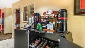 A coffee station with multiple coffee makers, a display of packaged oatmeal, and a refrigerated section with snacks.