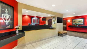 A reception area with a black counter, a 'WELCOME' sign, a bench, and a framed trophy on the wall.