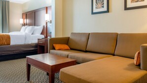 Ein Hotelzimmer mit einem Bett, einem Sofa, einem Couchtisch und zwei gerahmten Bildern an der Wand.