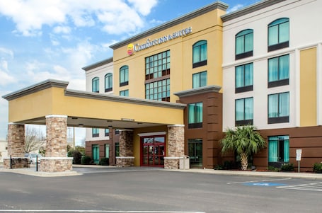 A hotel with a yellow facade, a covered entrance, and multiple windows.