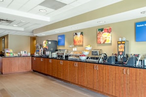 A buffet setup with various food stations, including a coffee machine and a fruit bowl.