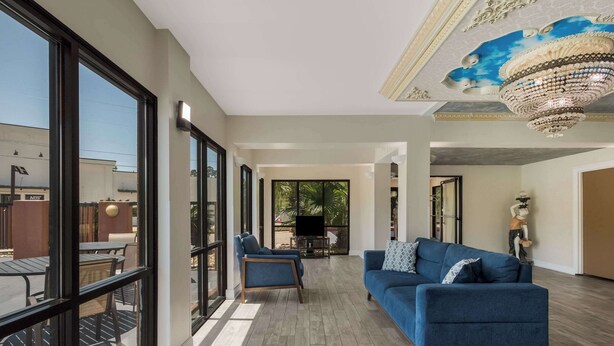 A spacious living area with a blue sofa, a coffee table, and a TV in the background.