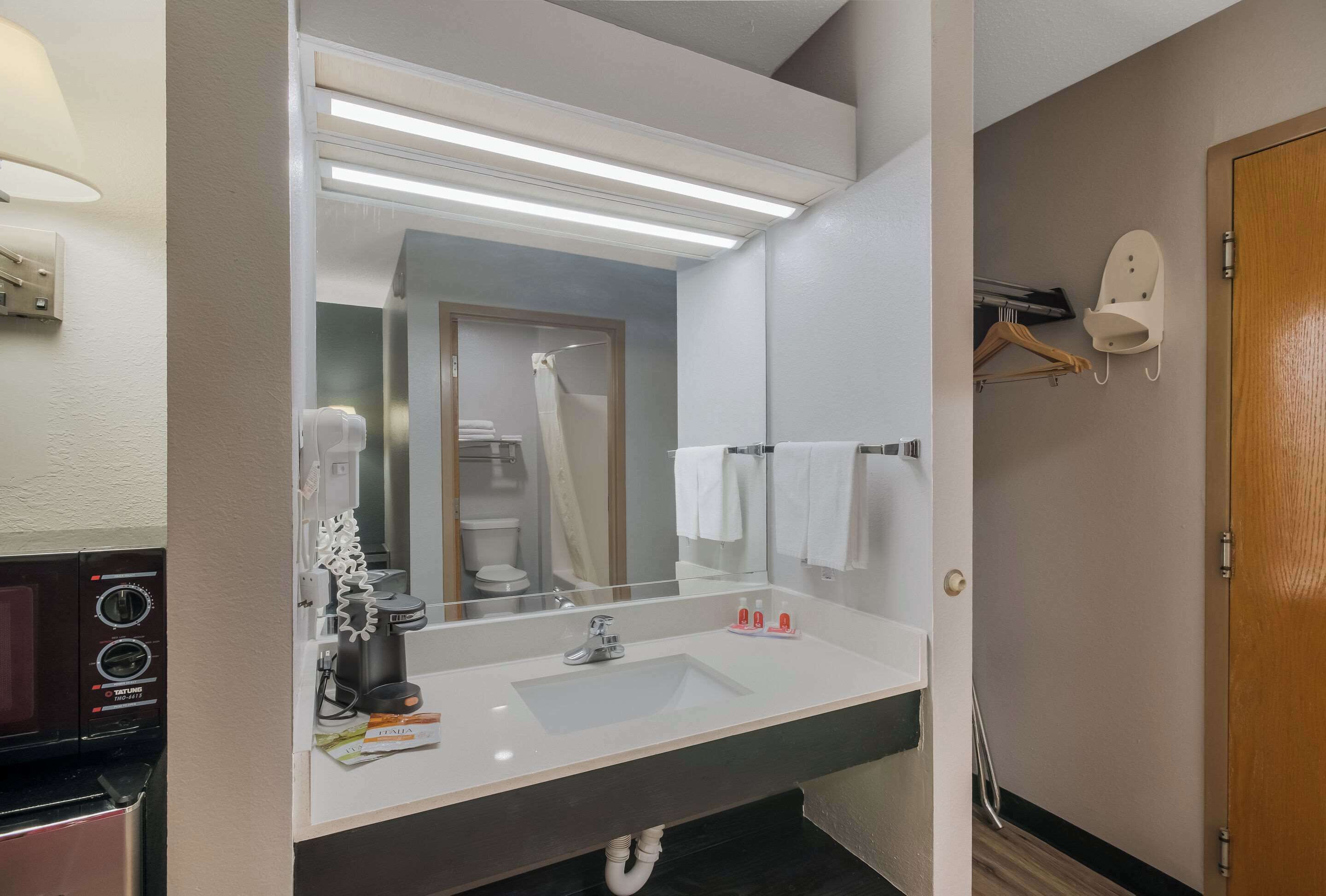 Un baño moderno con un espejo grande, un lavabo y una cafetera.