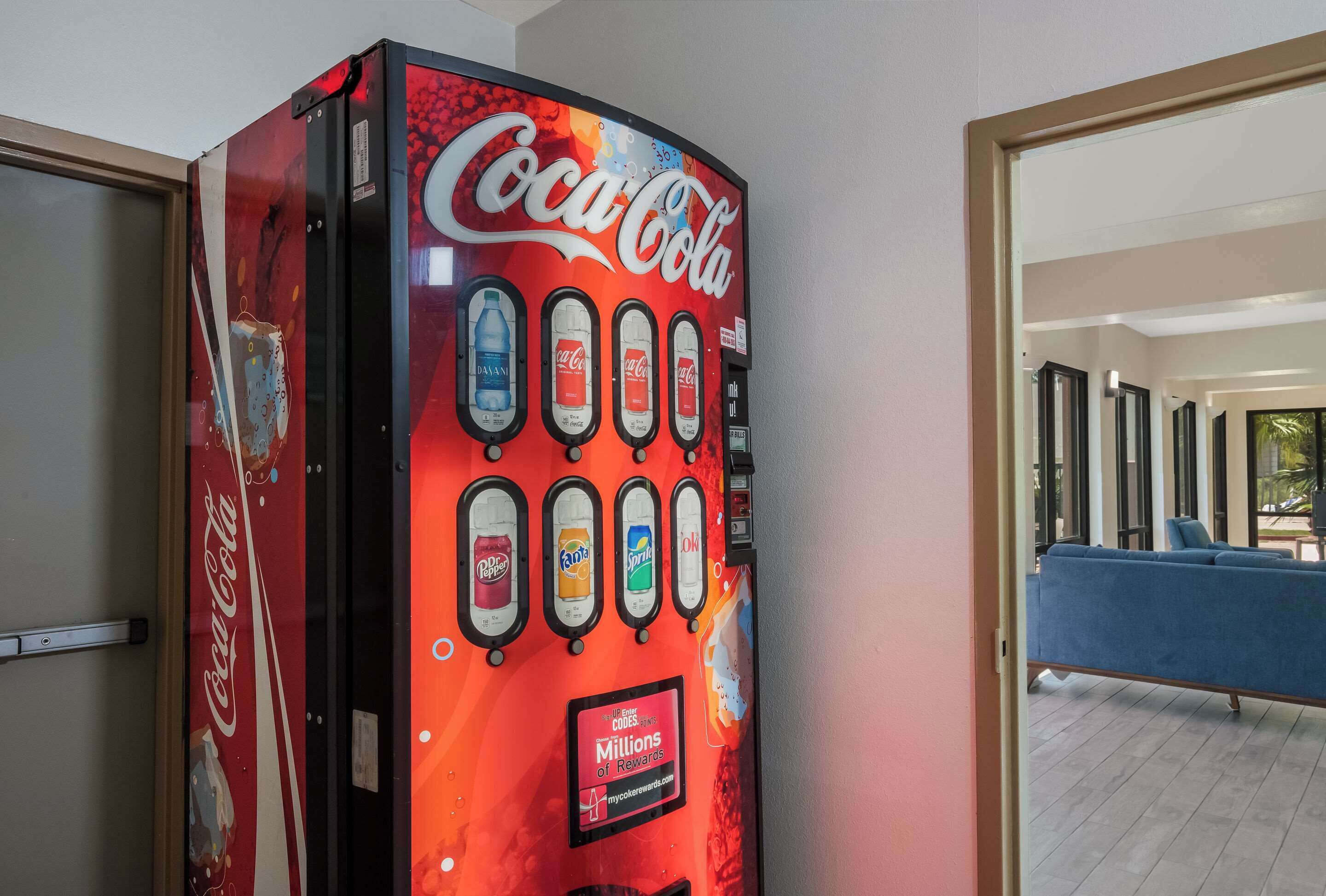 A Coca-Cola vending machine with multiple beverage options and a rewards program sign.