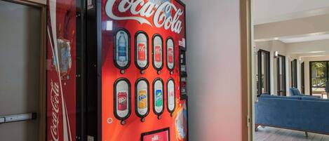 A Coca-Cola vending machine with multiple beverage options and a rewards program sign.