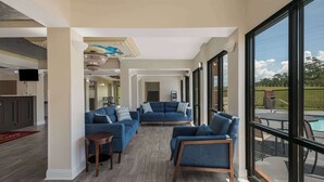 A spacious living area with a large window, a pool, and a kitchen area.
