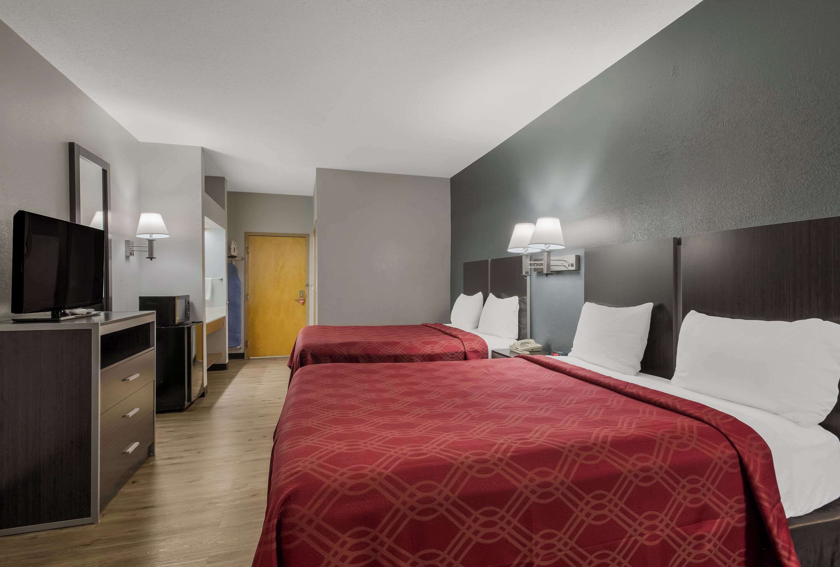 Een hotelkamer met twee bedden, een televisie, een bureau en een kledingkast.