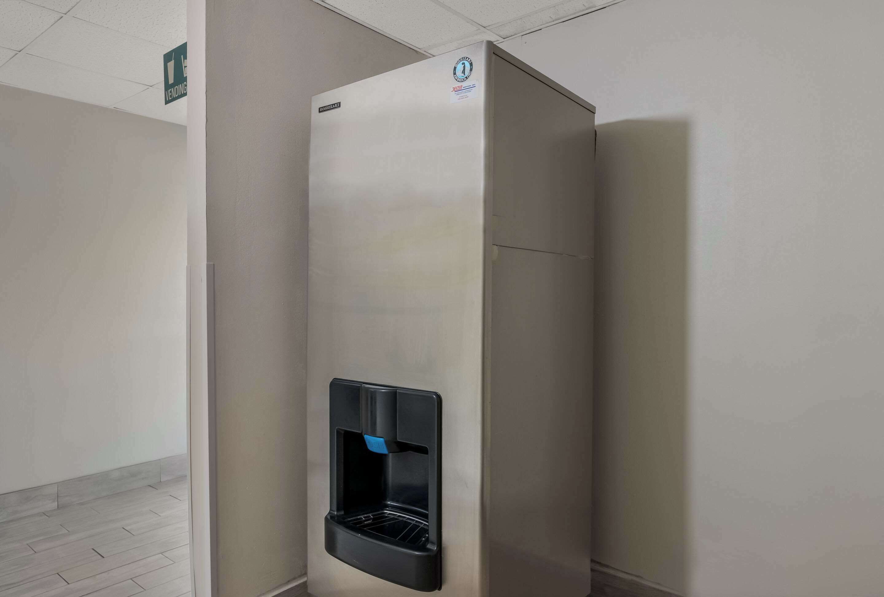 A stainless steel vending machine in a hallway with a "VENDING" sign above it.