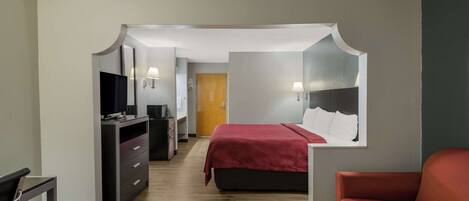 Ein Hotelzimmer mit Bett, Schreibtisch, Fernseher und einem roten Sofa.