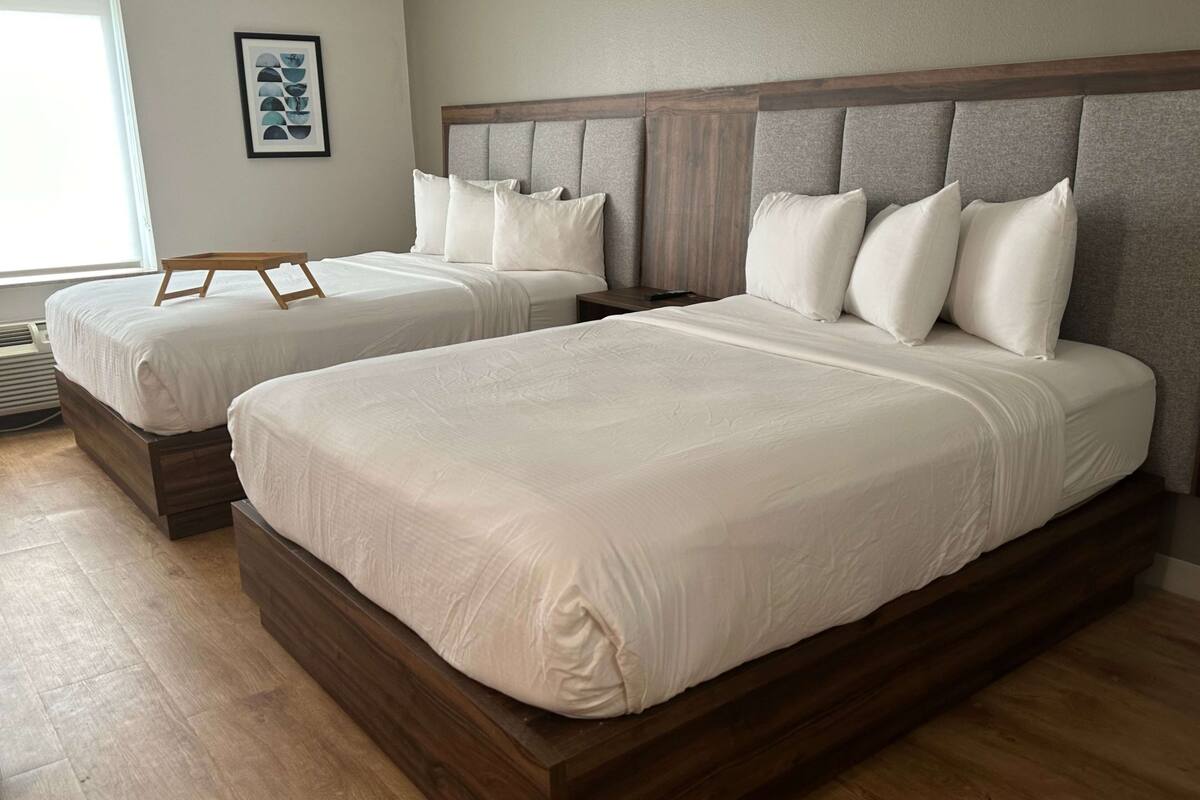 Una habitación de hotel con dos camas individuales, un cabecero de madera y un cuadro enmarcado en la pared.