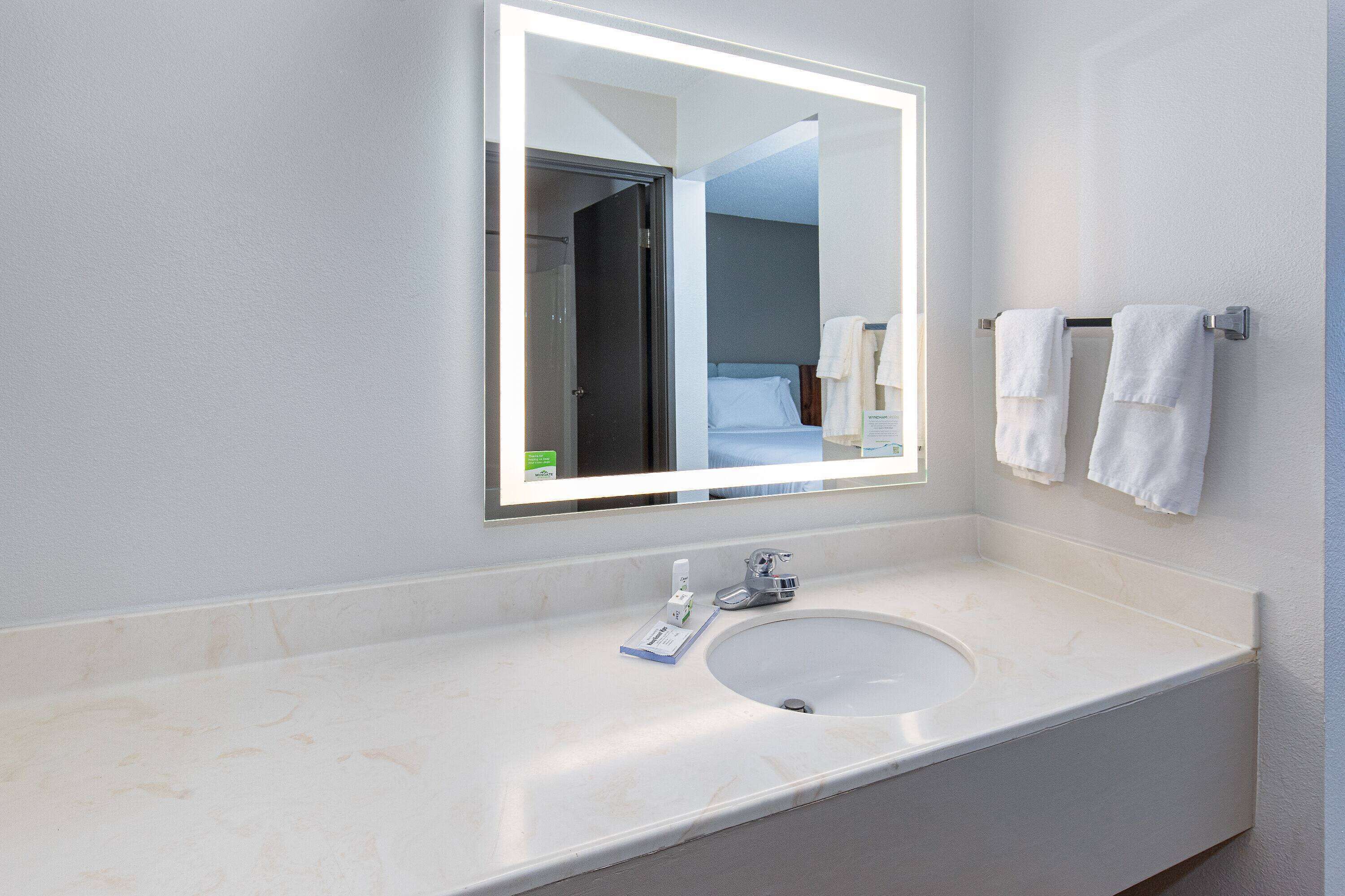 Un baño moderno con un espejo grande, un lavabo y dos toallas colgadas en la pared.