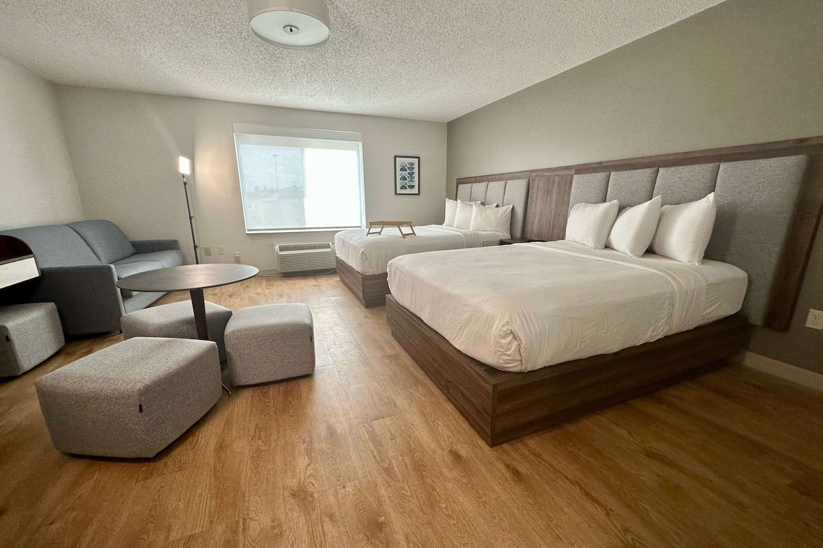 Una habitación de hotel moderna con una cama grande, un sofá, una mesita y un calentador portátil.