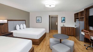 A hotel room with two beds, a small kitchenette, a round table, and a TV. - Wingate by Wyndham Hattiesburg (Hattiesburg)
