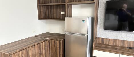 Una cocina con refrigerador empotrado, armarios de madera y televisor montado en la pared.