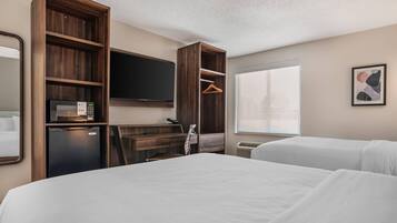 A hotel room with a bed, a desk with a computer, a television, and a window.