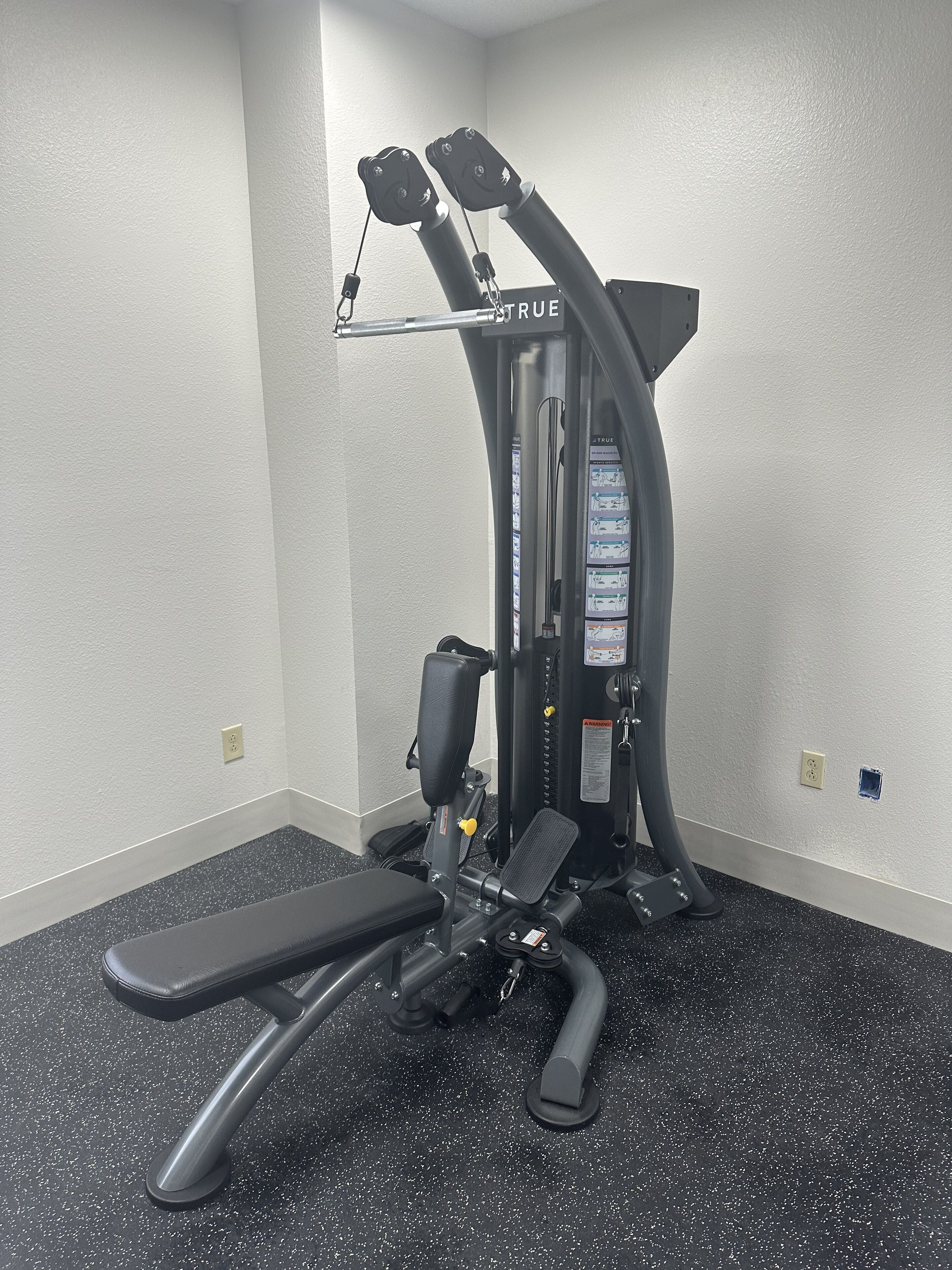 A gym with a bench, weight machines, and a wall-mounted mirror.