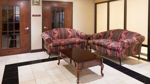 Una habitación con dos sofás estampados, una mesa de centro de madera y una puerta que indica 'Great Room 3'.