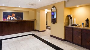 Un vestíbulo de hotel con una recepción, una máquina de café y un espejo en la pared.