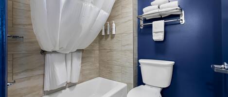 Uma casa de banho moderna com banheira, sanita e porta-toalhas.