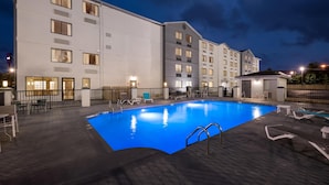 Un hotel con piscina, zona de estar al aire libre y fachada iluminada.