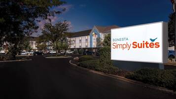 Entrada de un hotel con un letrero grande que dice 'Sostenis Simply Suites'.