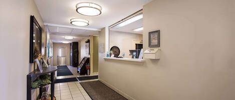 Un pasillo de hotel con una consola negra, un espejo y un mostrador de recepción.
