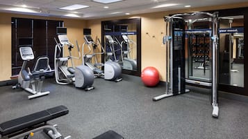 Un gimnasio con cintas de correr, elípticas, una banca y una pelota de medicina.