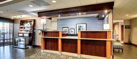A reception area with a wooden reception desk, a patterned rug, and a vending machine.