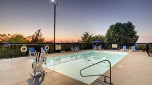 A swimming pool with lounge chairs and a lifeguard stand.