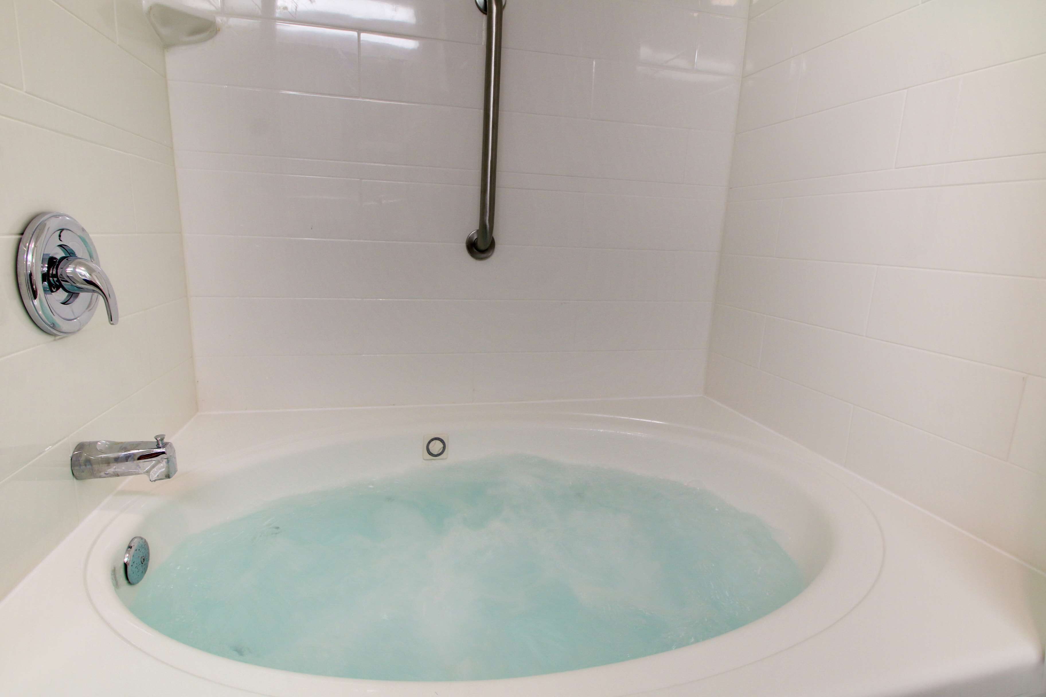 A bathtub with a handheld showerhead, a built-in faucet, and a drain.