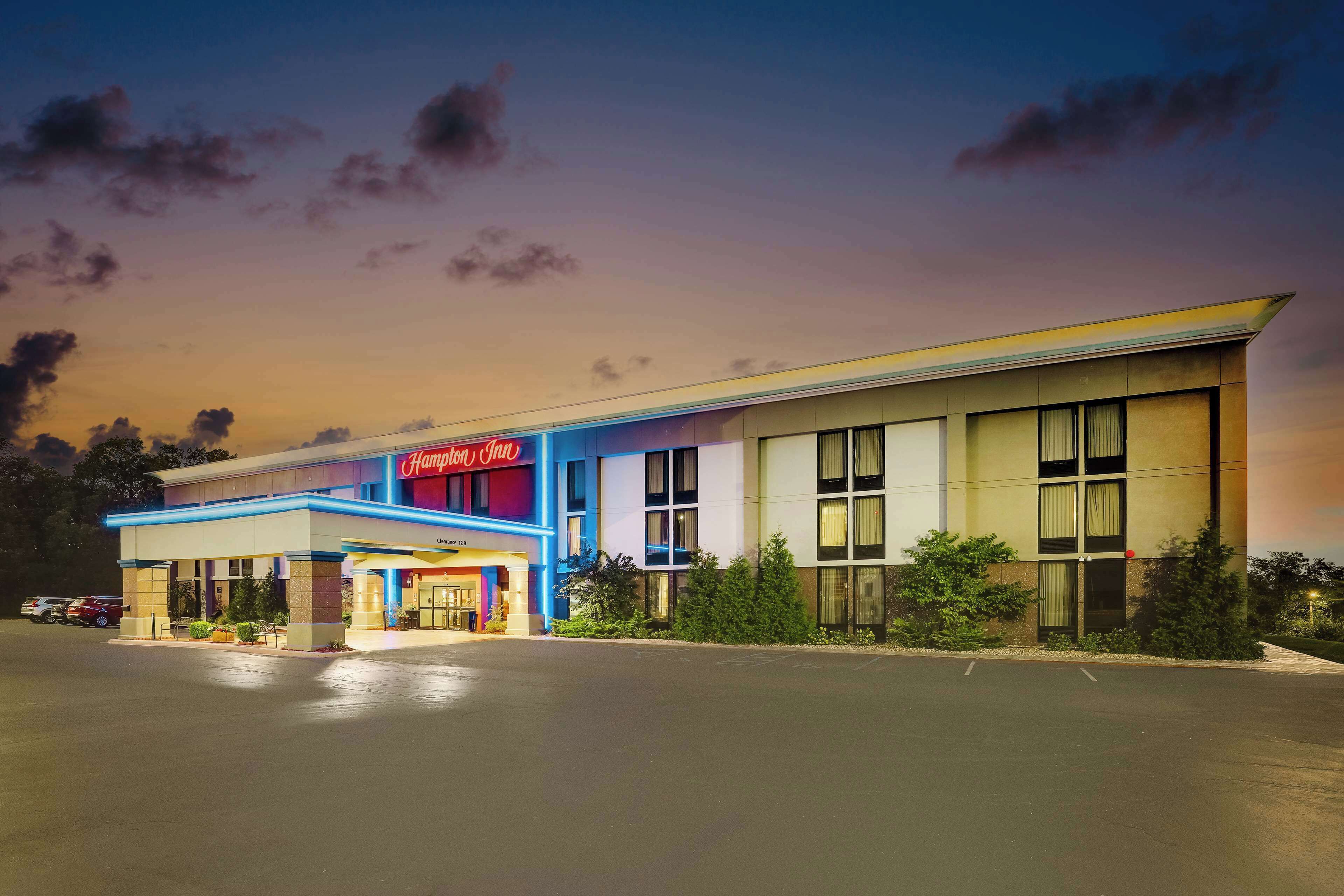 A hotel with a prominent "Hampton Inn" sign, a covered entrance, and a parking lot.