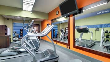 A gym with treadmills, exercise bikes, and a mirrored wall with motivational text.