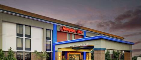 A Hampton Inn hotel with a clear entrance, a sign indicating a 12'9" clearance, and a welcoming sign.