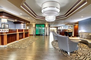 A hotel lobby with a reception desk, seating area, and a green glass door. - Hampton Inn Rolla (Rolla)